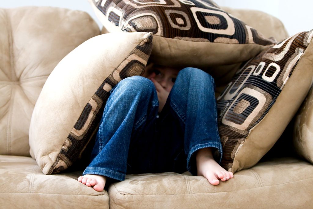 Upset little boy hiding in pillow expressing tantrum behavior